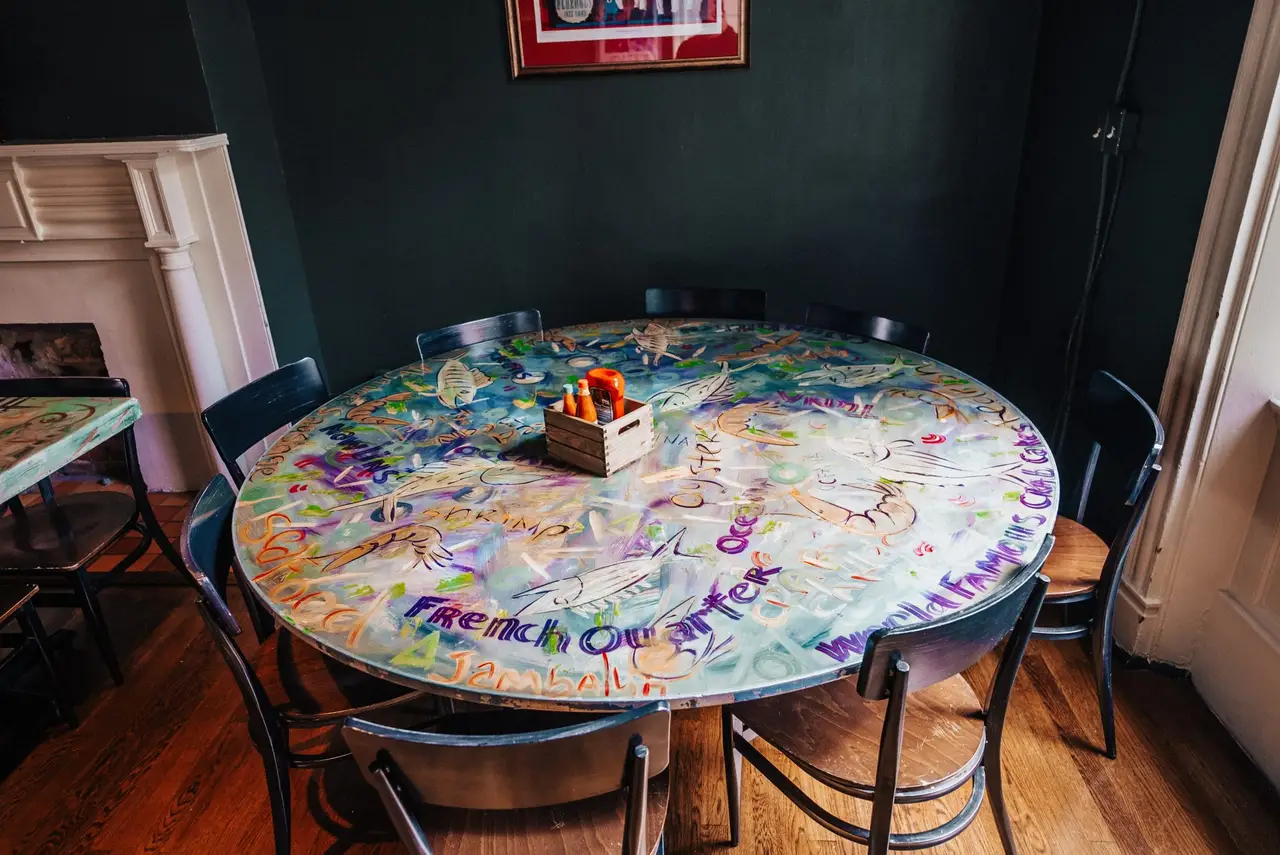 Round table hand-painted with French Quarter scenes in the Mardi Gras Room