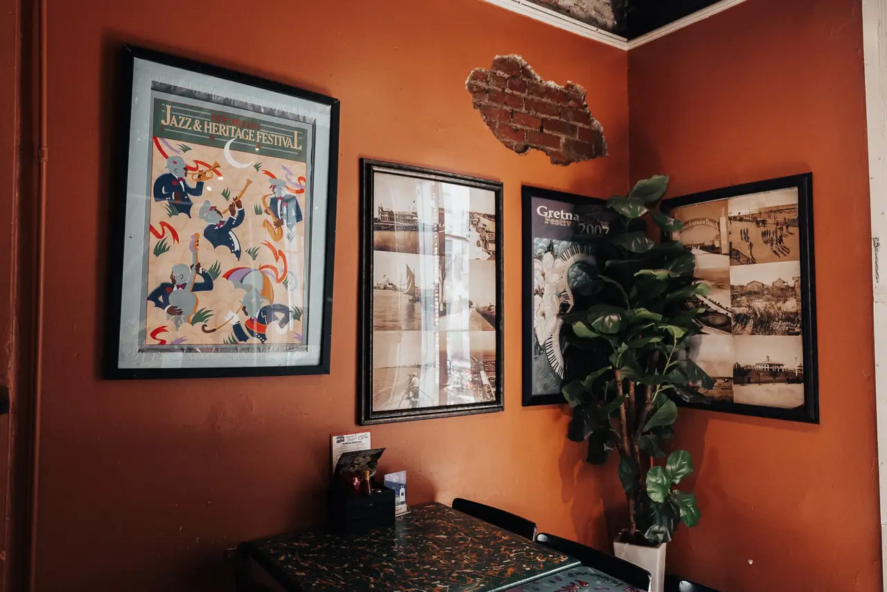 Framed New Orleans prints on the Royal Room’s orange walls