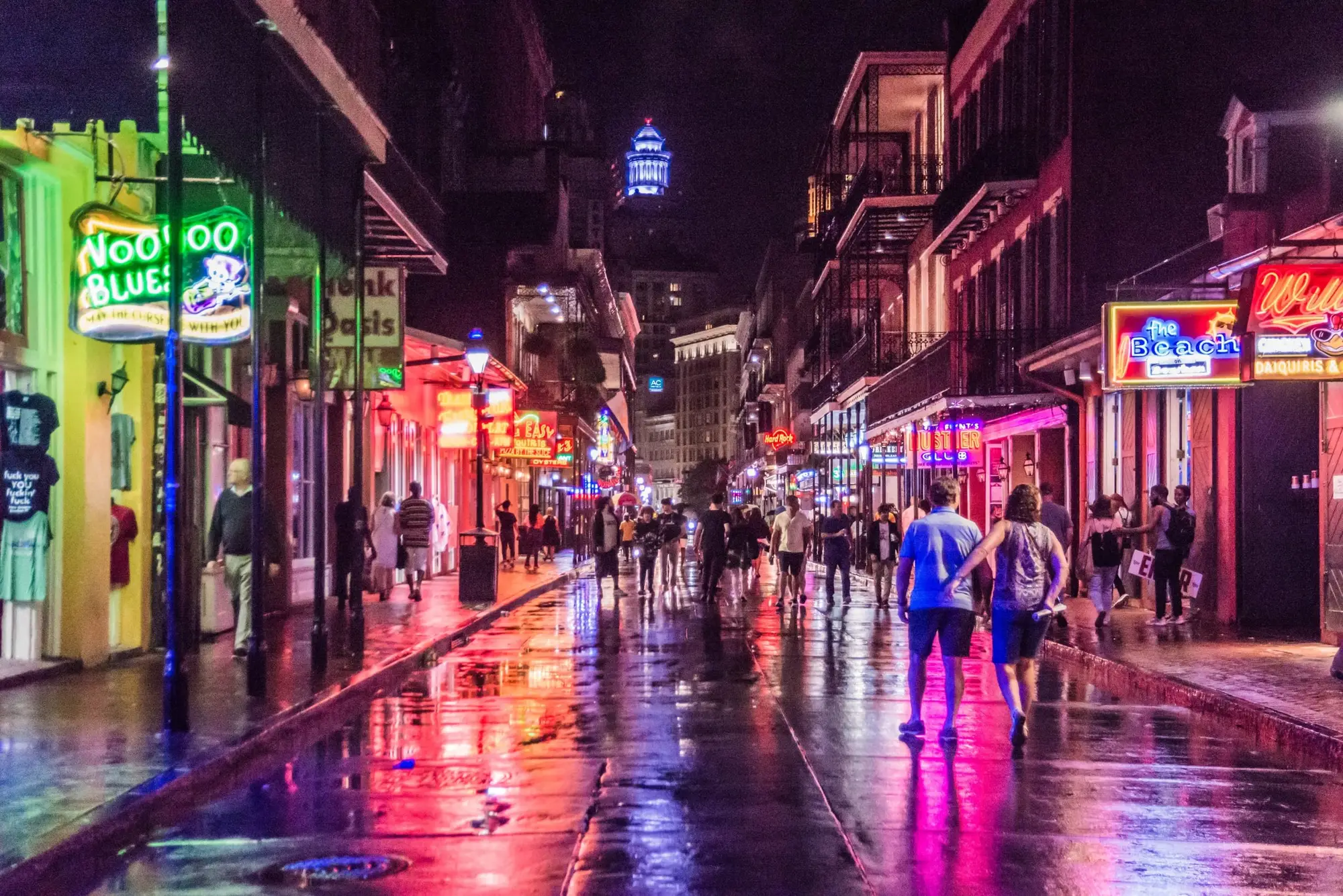 Bourbon Street at night, neon signs reflected on the wet pavement