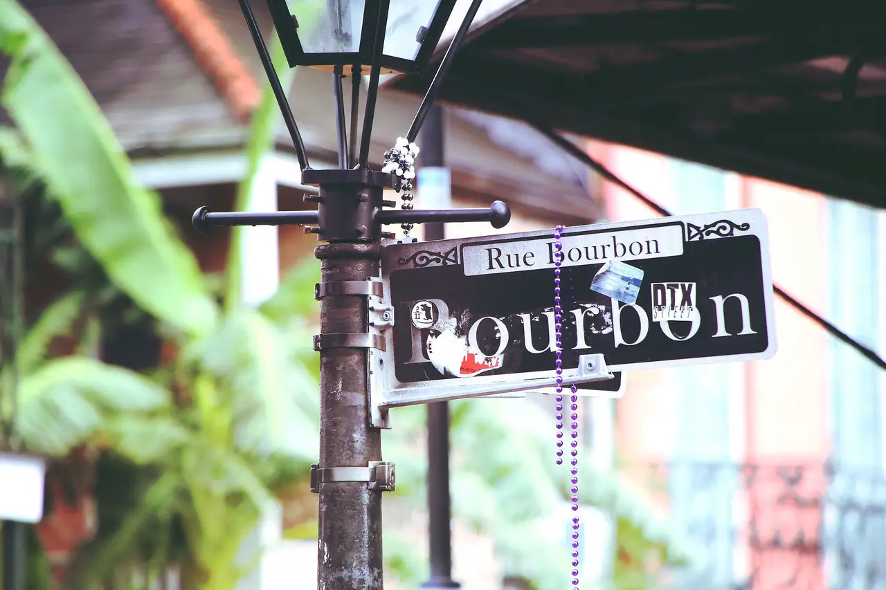Rue Bourbon street sign on a lamppost hung with Mardi Gras beads