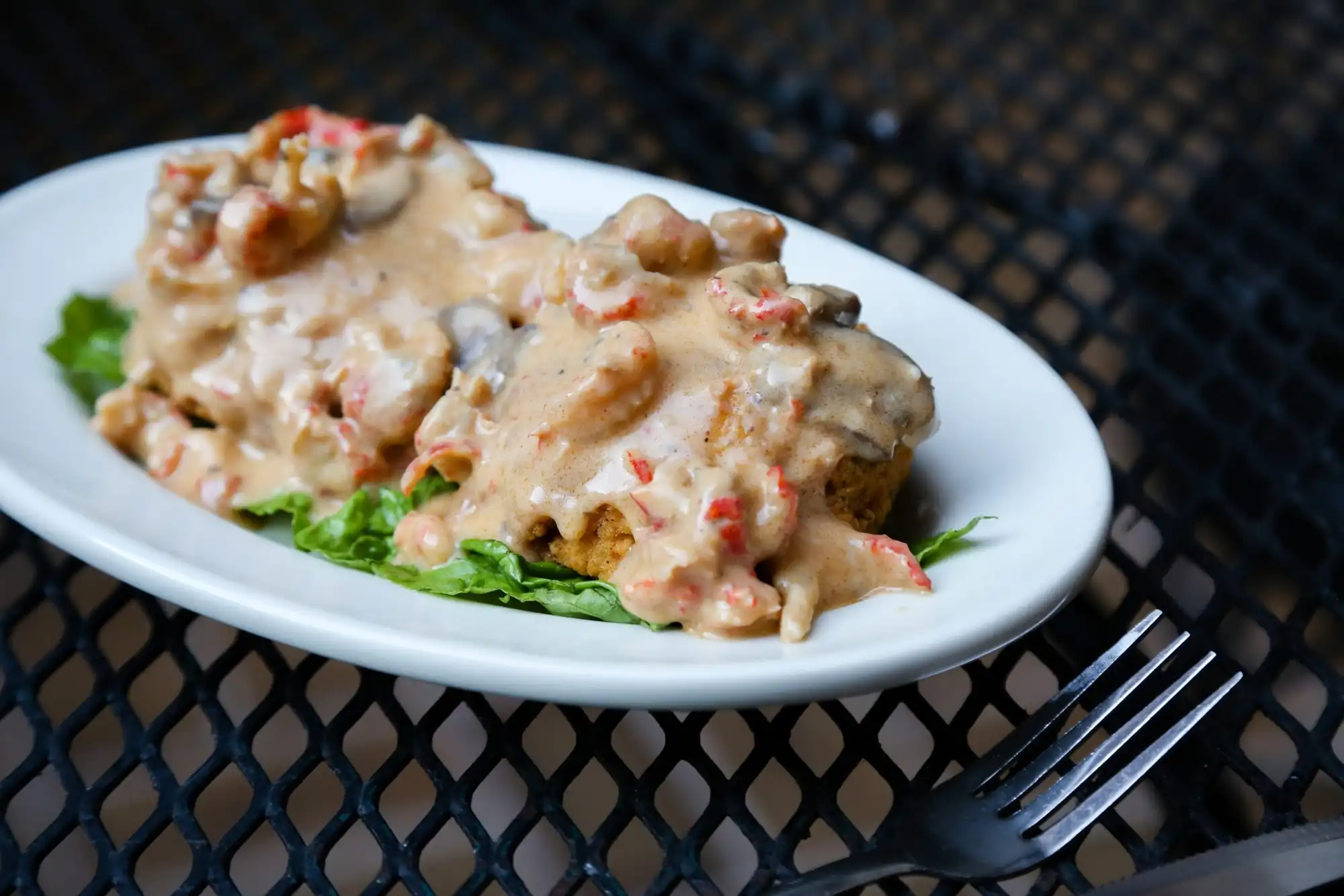 Louisiana crabmeat cake smothered in crawfish mushroom cream sauce on a white plate