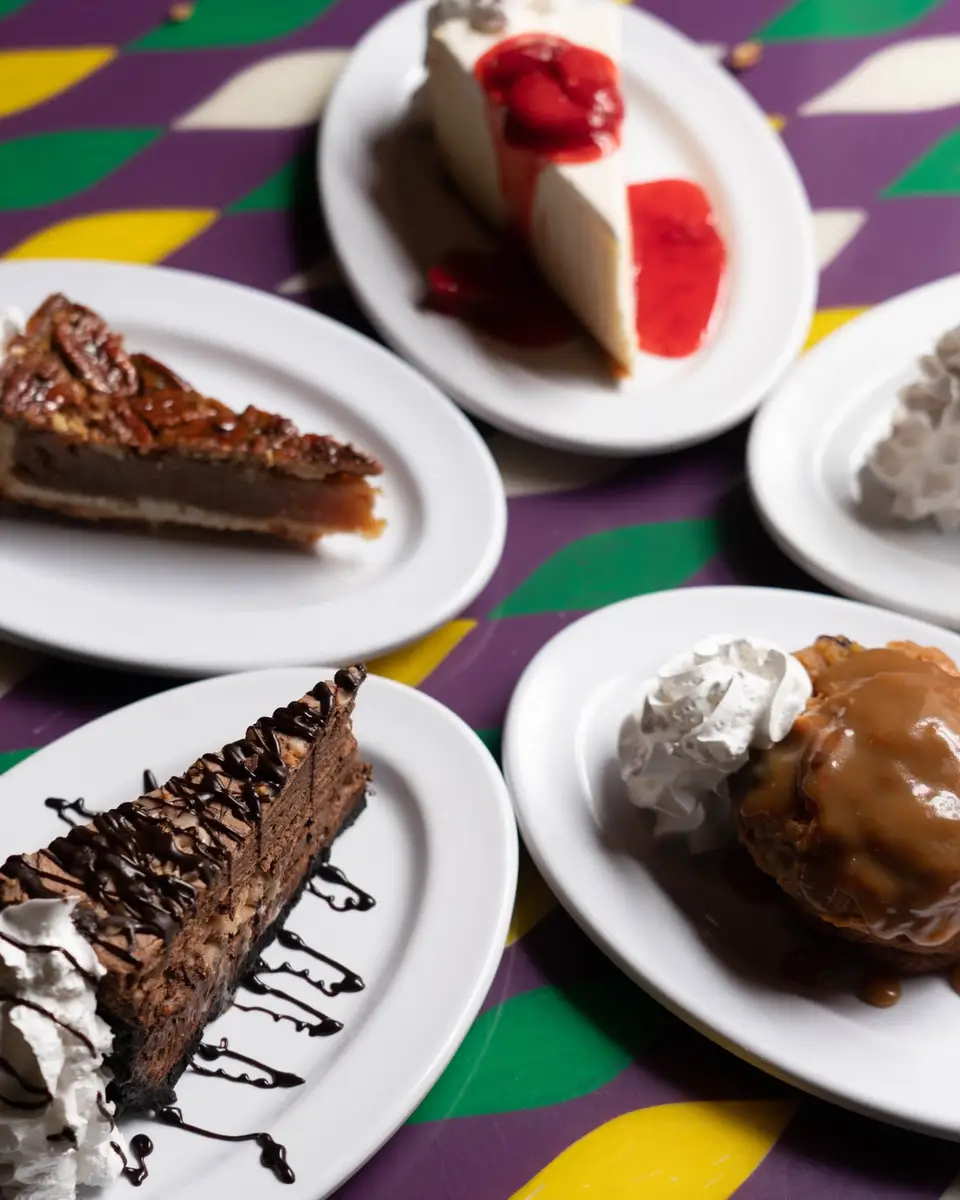 Bread pudding, pecan pie, cheesecake and chocolate mousse on a Mardi Gras-striped table