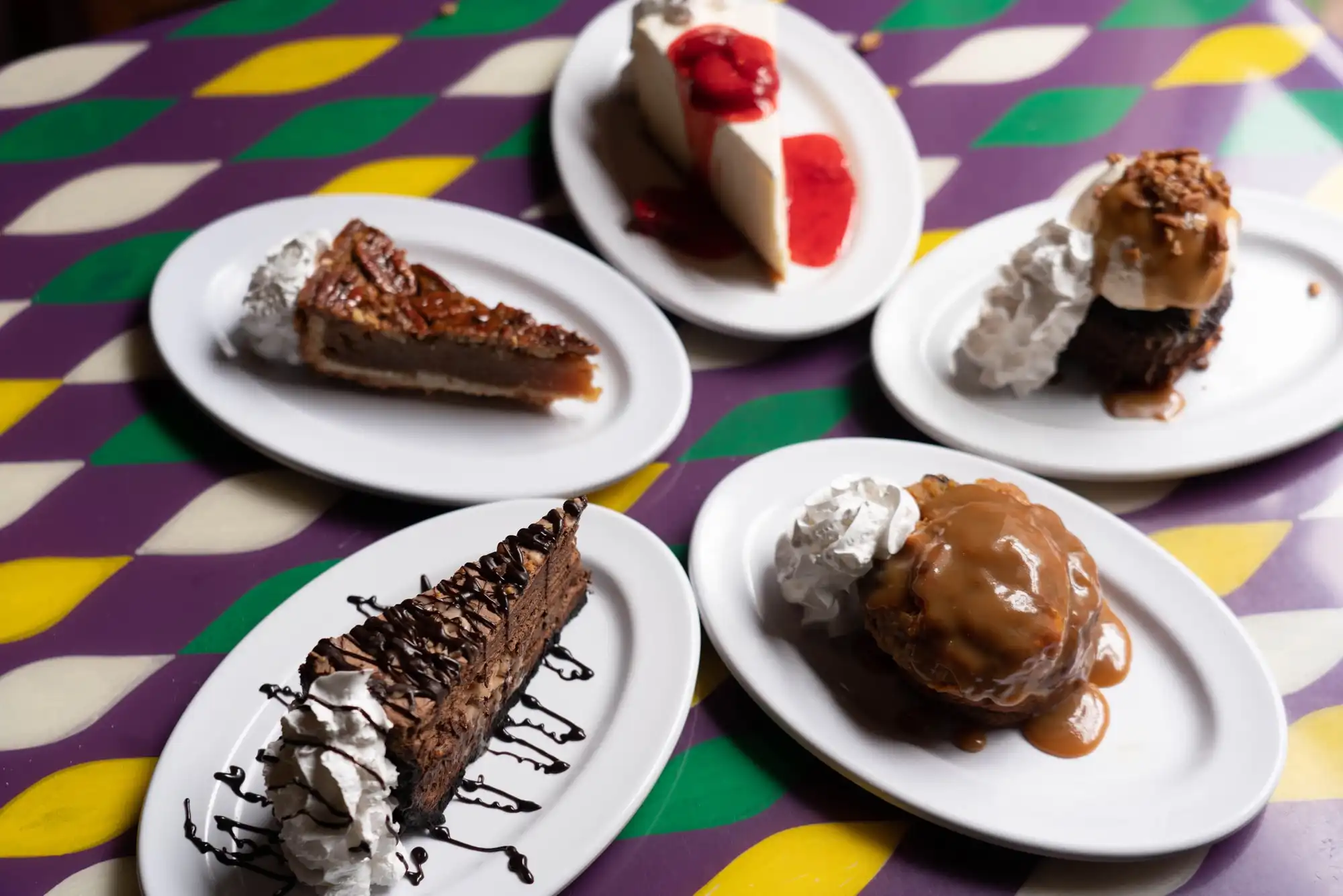 Bread pudding, pecan pie, cheesecake and chocolate mousse on a Mardi Gras-striped table